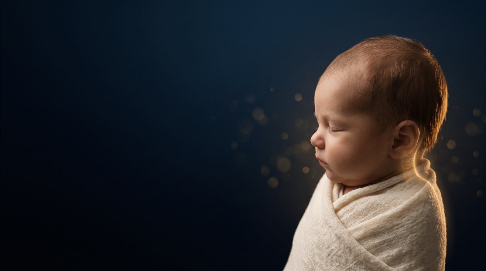 A peaceful swaddled newborn in profile, gold-lit against deep navy with soft golden light — gentle newborn subluxation care at Rochet Family Chiropractic, Royal Palm Beach FL